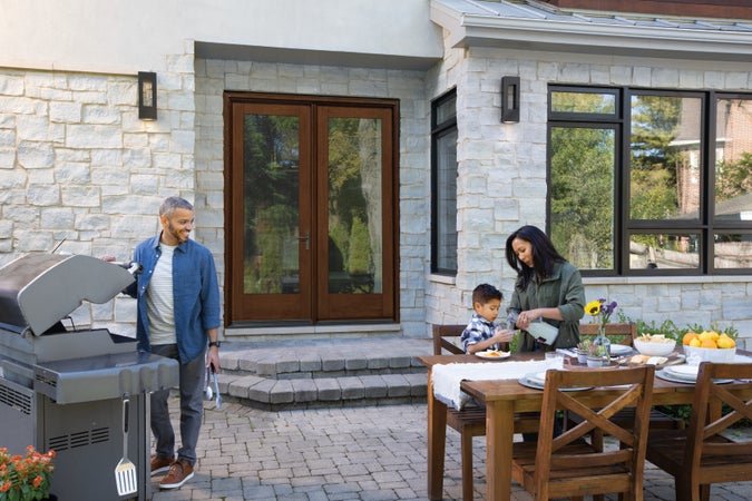 A New Earth colored Classic Craft Entry Door with a family outside on the patio grilling