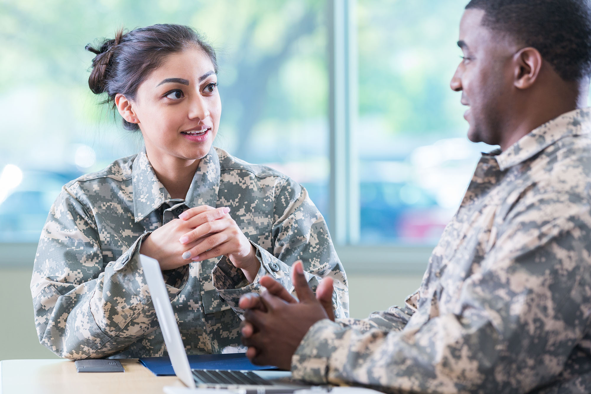 Woman and man in military uniforms sitting down and talking to each other.
