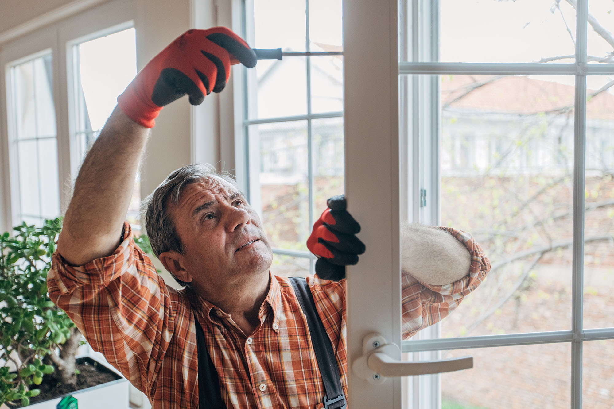 Man replacing a door of a home as he uses a screw on the door hinge.