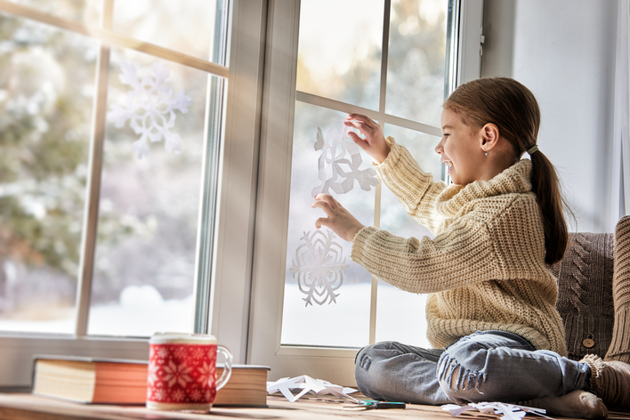 A little girl decorating a window for Christmas