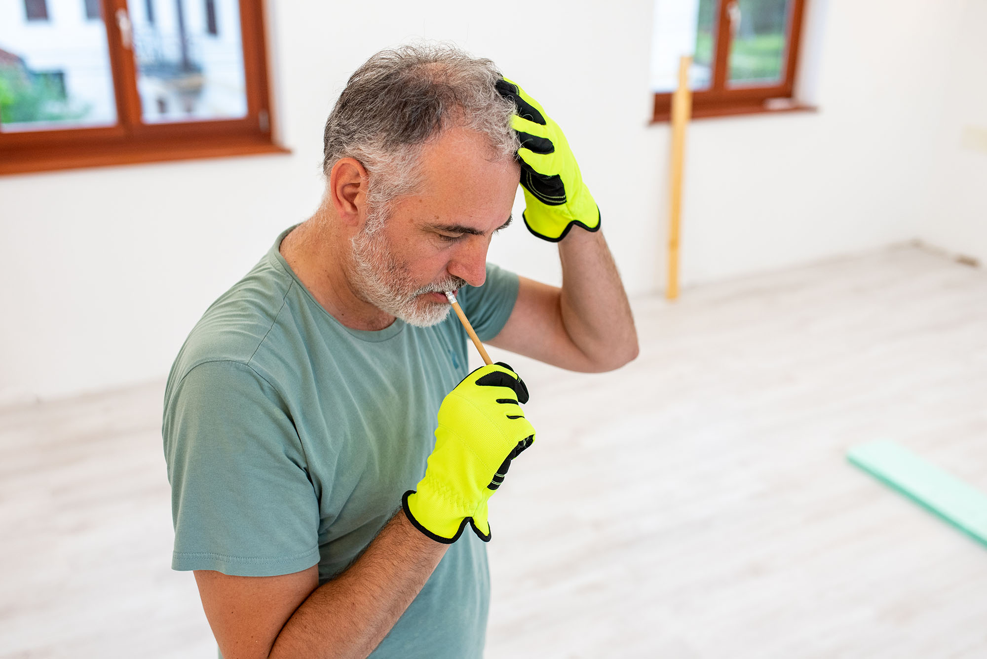 A man considering DIY home renovation ideas while wearing work gloves and considering his workspace.