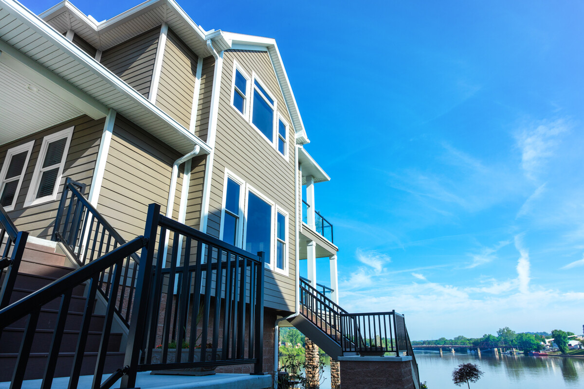 Picture windows on a multi-story home with a lake view in the background