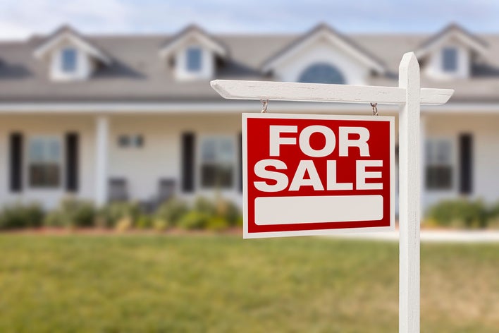 For sale sign in front of a large home.