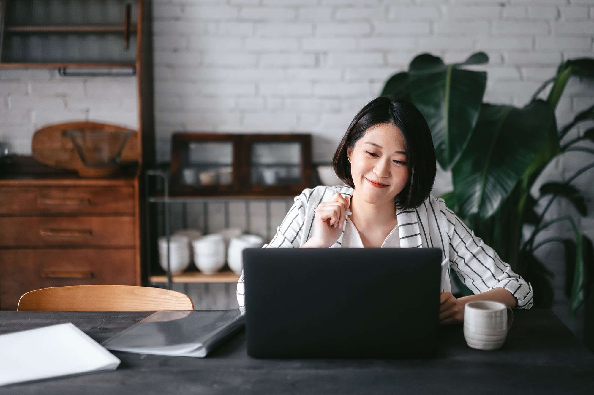 A woman working in a naturally lit space on her laptop.
