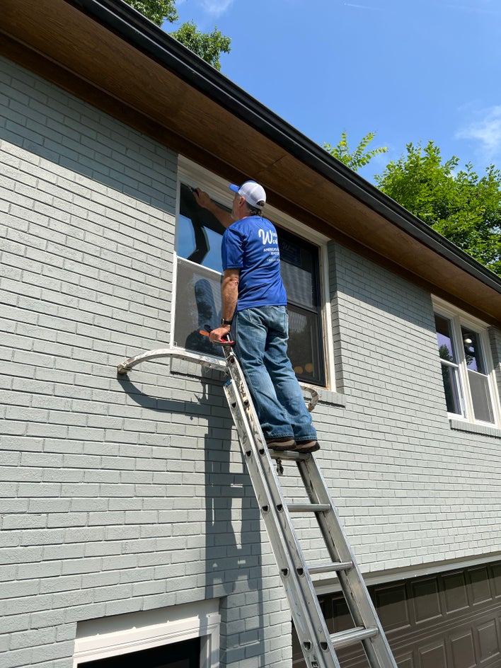A window world installer putting a new replacement window into a home