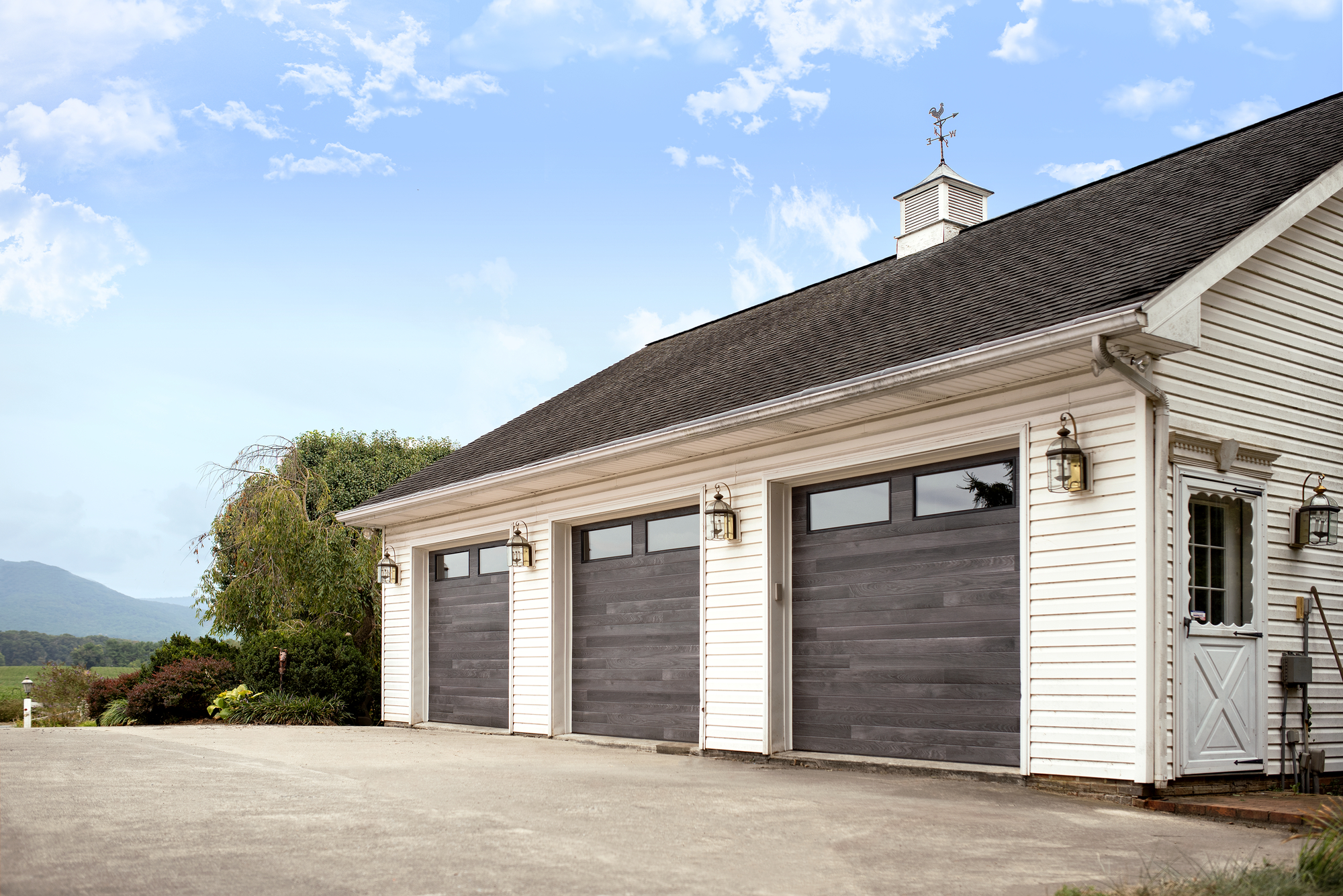 Carbon oak garage door with clear windows on a garage with white siding