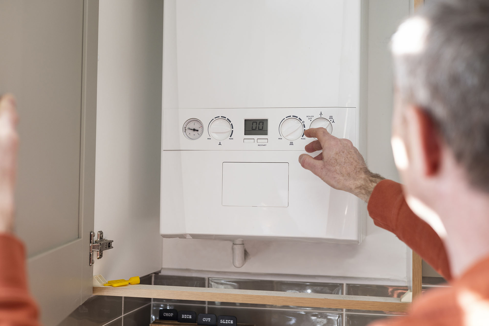 Person lowering the water heater temperature in their home to help reduce the electric bill during winter.