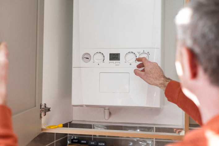 Person lowering the water heater temperature in their home to help reduce the electric bill during winter.