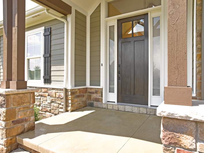 A dark woodgrain fiberglass door at the entrance of a craftsman-style house.