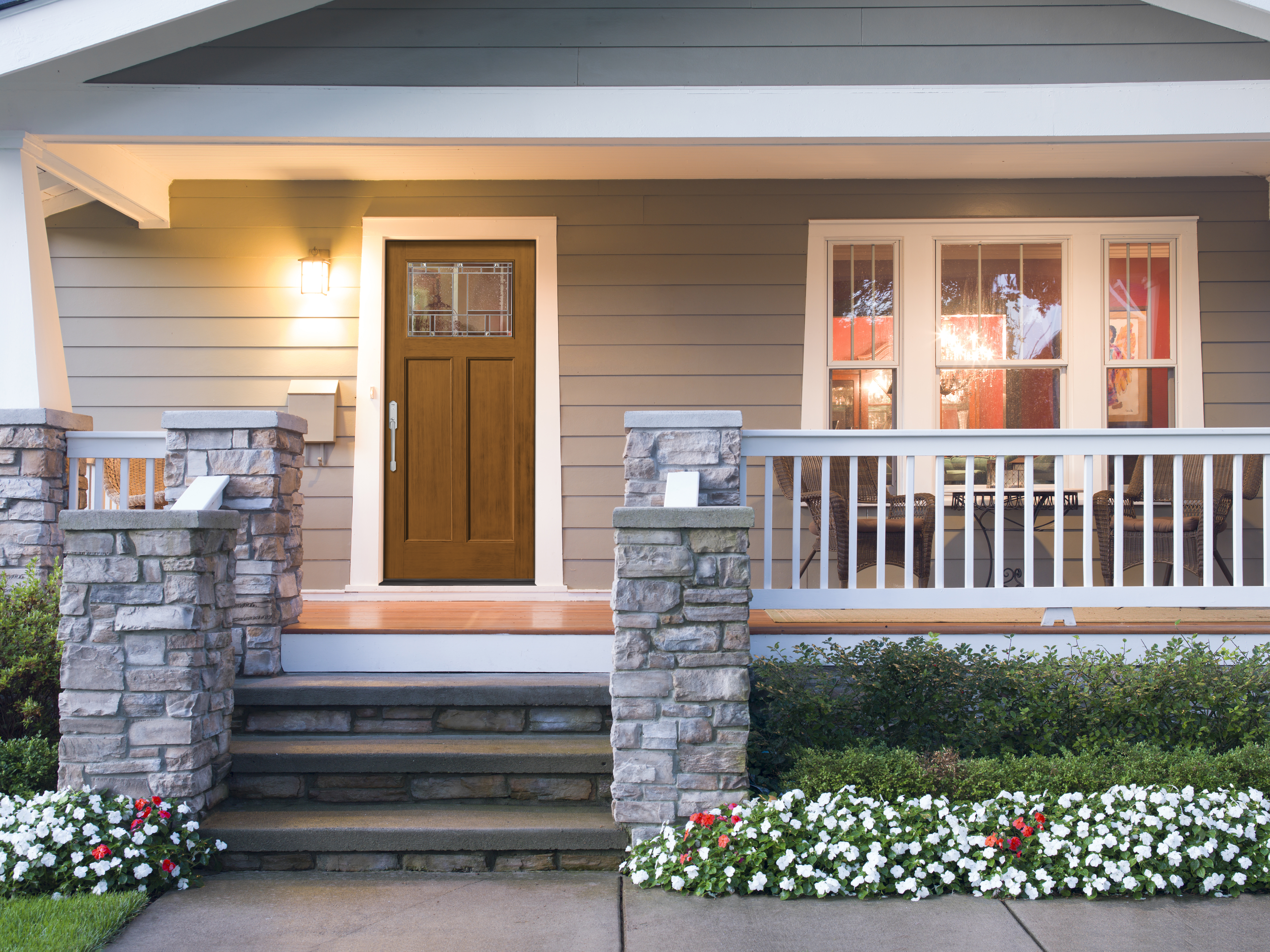 A Wildflower Honey stained Classic Craft Entry Door under a porch that has a light turned on