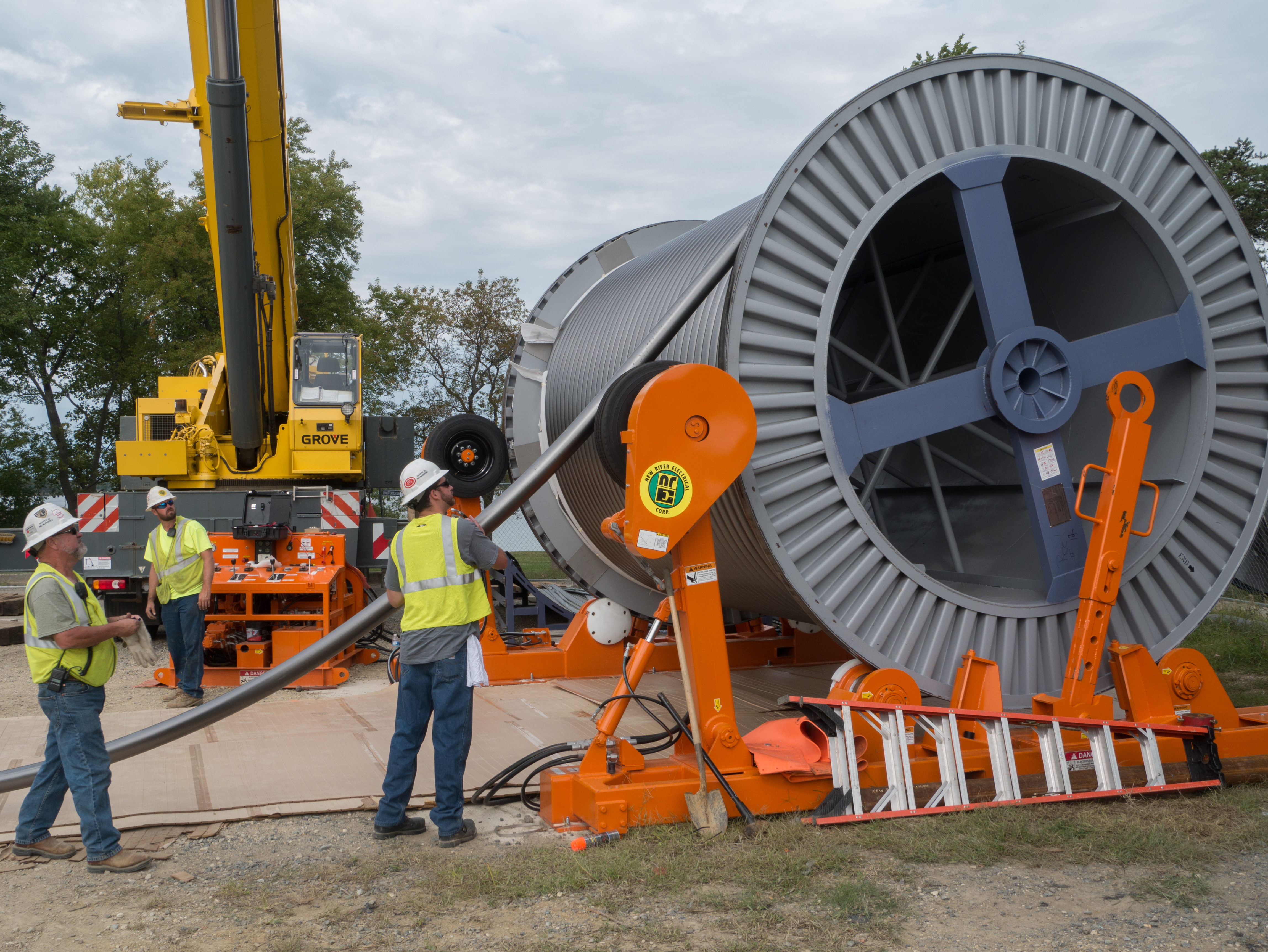 Construction workers unspooling underground transmission cable