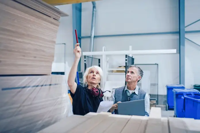 Two people in a warehouse for wood and furniture