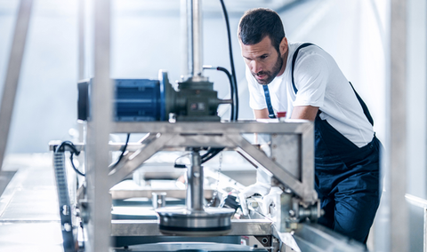 A worker is working on a production line machine in a factory.