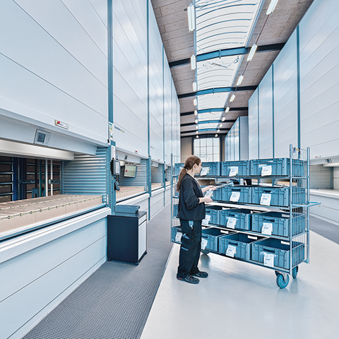 Woman works on the Kardex Shuttle and puts order in a picking trolley