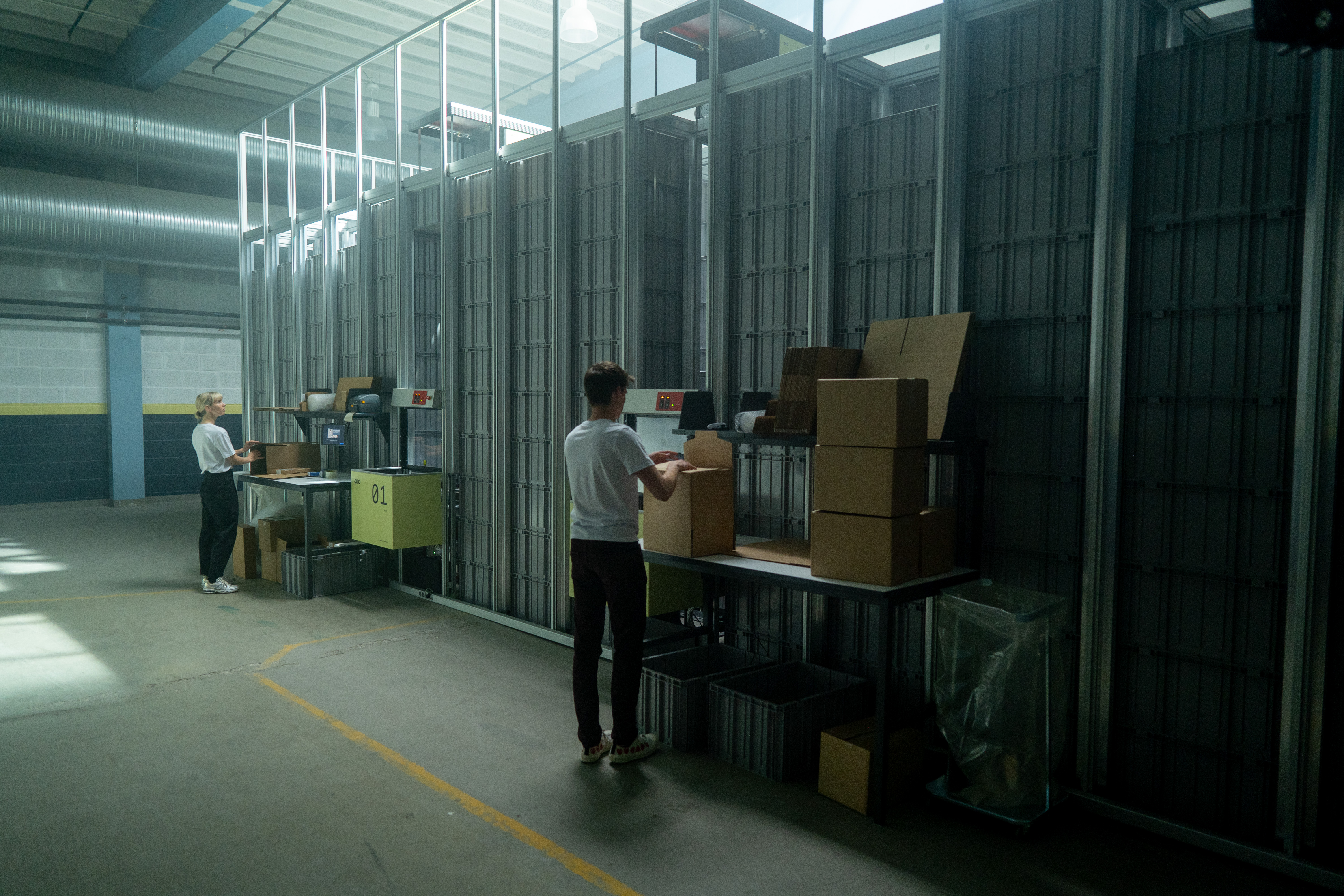 Two warehouse operators folding boxes at Pio workstation