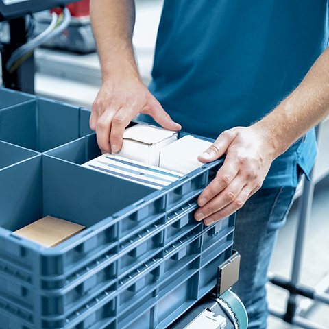 Muž vybírá předměty z Kardex Miniload-in-a-Box (dříve Kardex Compact Buffer) pomocí Kardex VBM Boxů. 