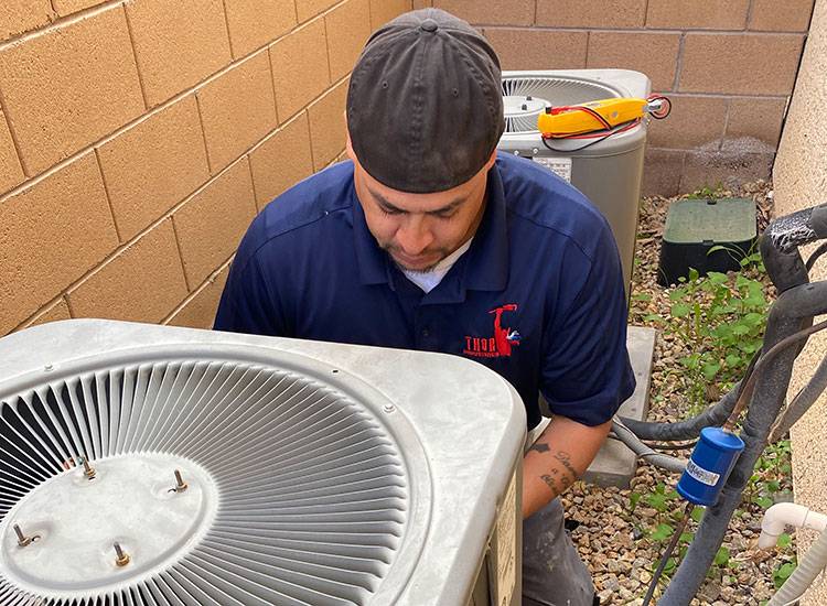 Technician performing maintenance on residential HVAC units outdoors, ensuring top quality service.