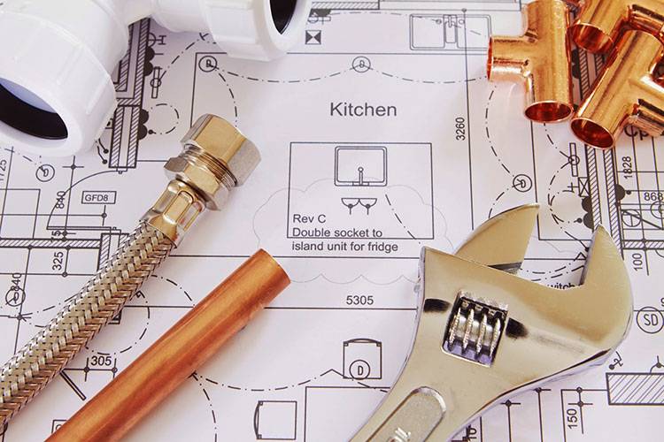 Plumbing tools and copper pipes on a kitchen blueprint indicating new pipe installation service