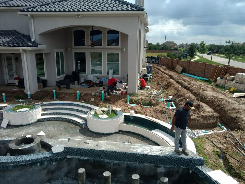 High-end backyard pool construction with modern design and detailed landscaping.
