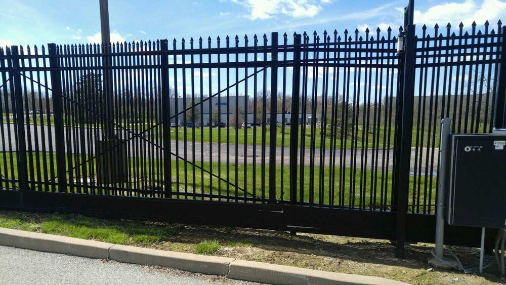 Tall metal security fence with spear-topped bars surrounding a property.