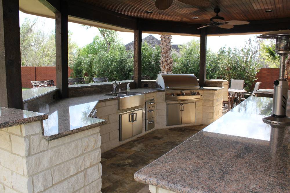 Outdoor kitchen with stainless steel grill and granite countertops under a covered pavilion