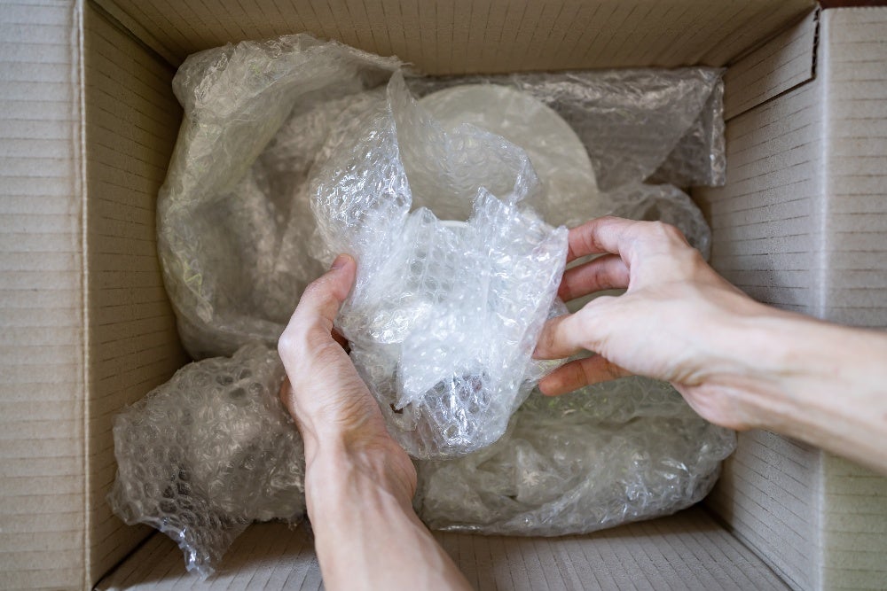 Wrapping fragile item with bubble wrap in a cardboard box