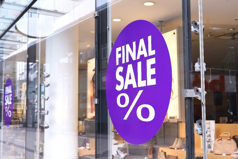 Glass storefront with final sale signs promoting discounts