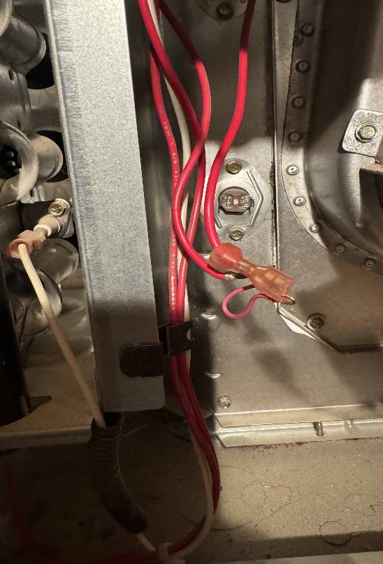 The internal wiring of a residential HVAC system shows red and white wires connected to electrical components