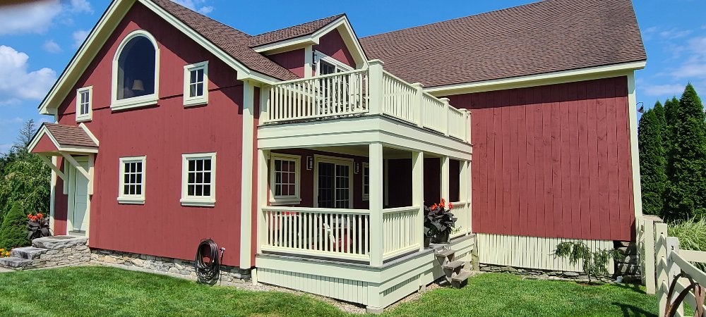 A beautifully painted red home exterior with a white porch by expert house painters.