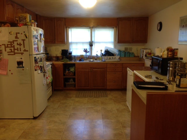 Cluttered kitchen with wood cabinets and appliances