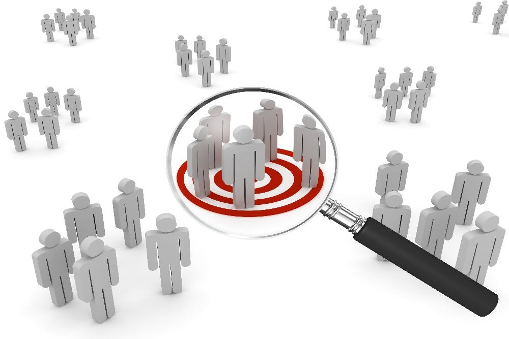 Magnifying glass focusing on target audience group on red bullseye target