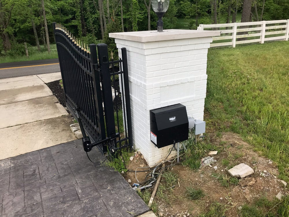 An automated gate system installed on a driveway with electrical connections.