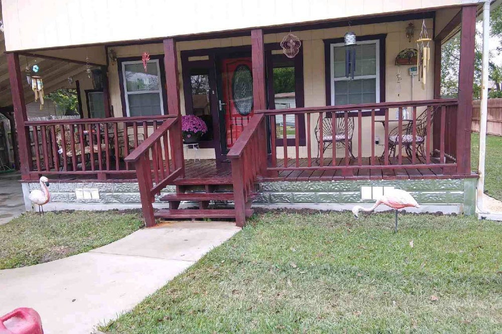 House foundation with raised porch, wooden railings, and decorative steps.