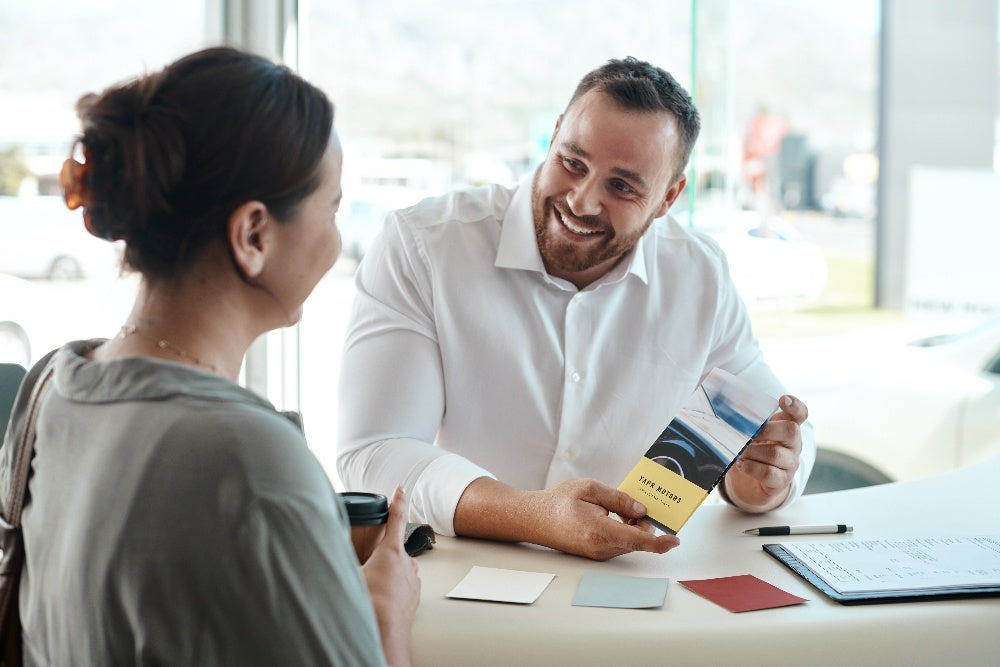 Man showing real estate brochure to woman in office