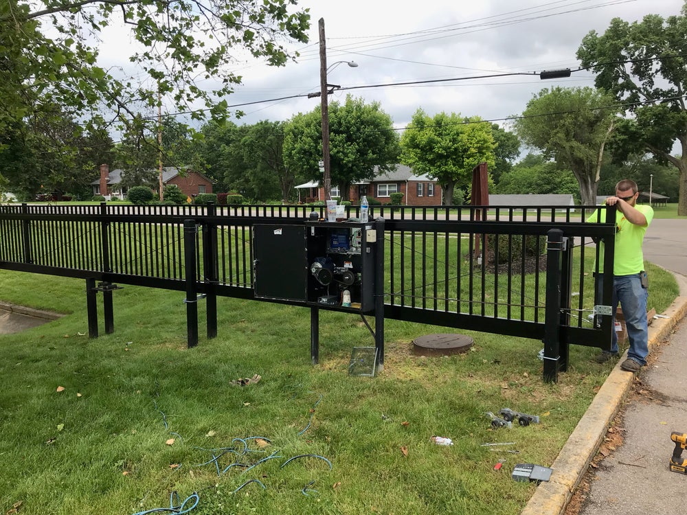 A technician inspecting or repairing an automatic gate motor