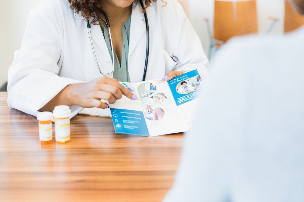 A doctor explains healthcare services using an informative brochure during a consultation