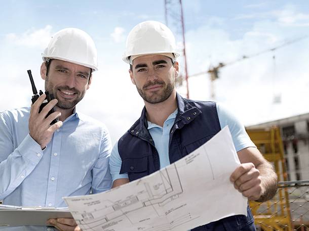 Construction contractors with building plans and walkie-talkie on site