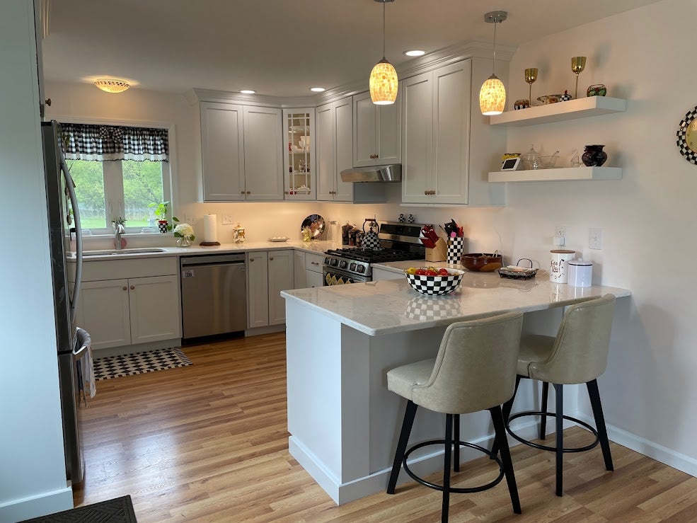 Renovated kitchen with white cabinets, marble countertops, and island seating.