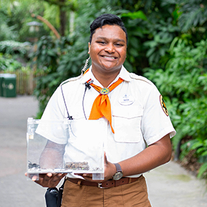 Disney Wilderness Explorer intern holding a clear box of insects and smiling