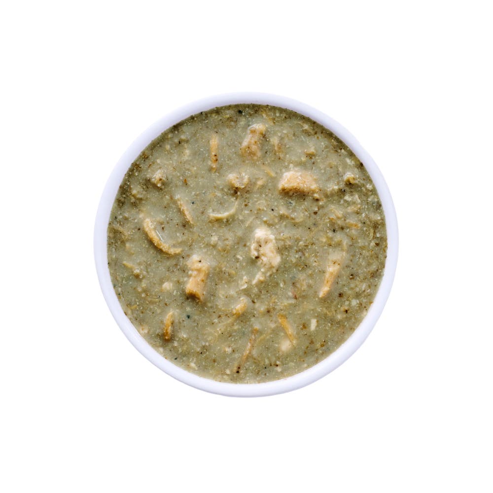 Top view of a white bowl filled with Wild Alaska pollock and chicken stew cat food, showing a moist, chunky texture with visible pieces of chicken and fish in a light gravy on a white background.