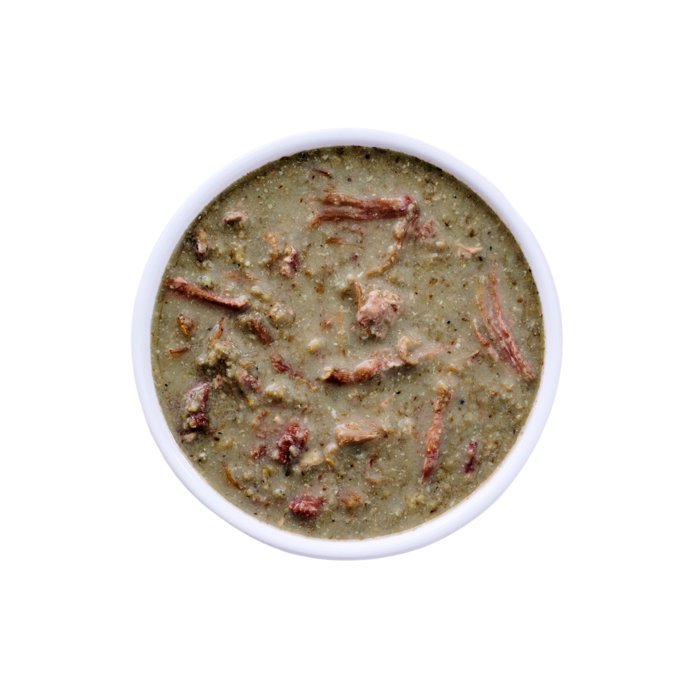 Top view of a white bowl filled with Wild Alaska pollock and pork stew cat food, showing a moist, chunky texture with visible pieces of pork and fish in a light gravy on a clean white background.