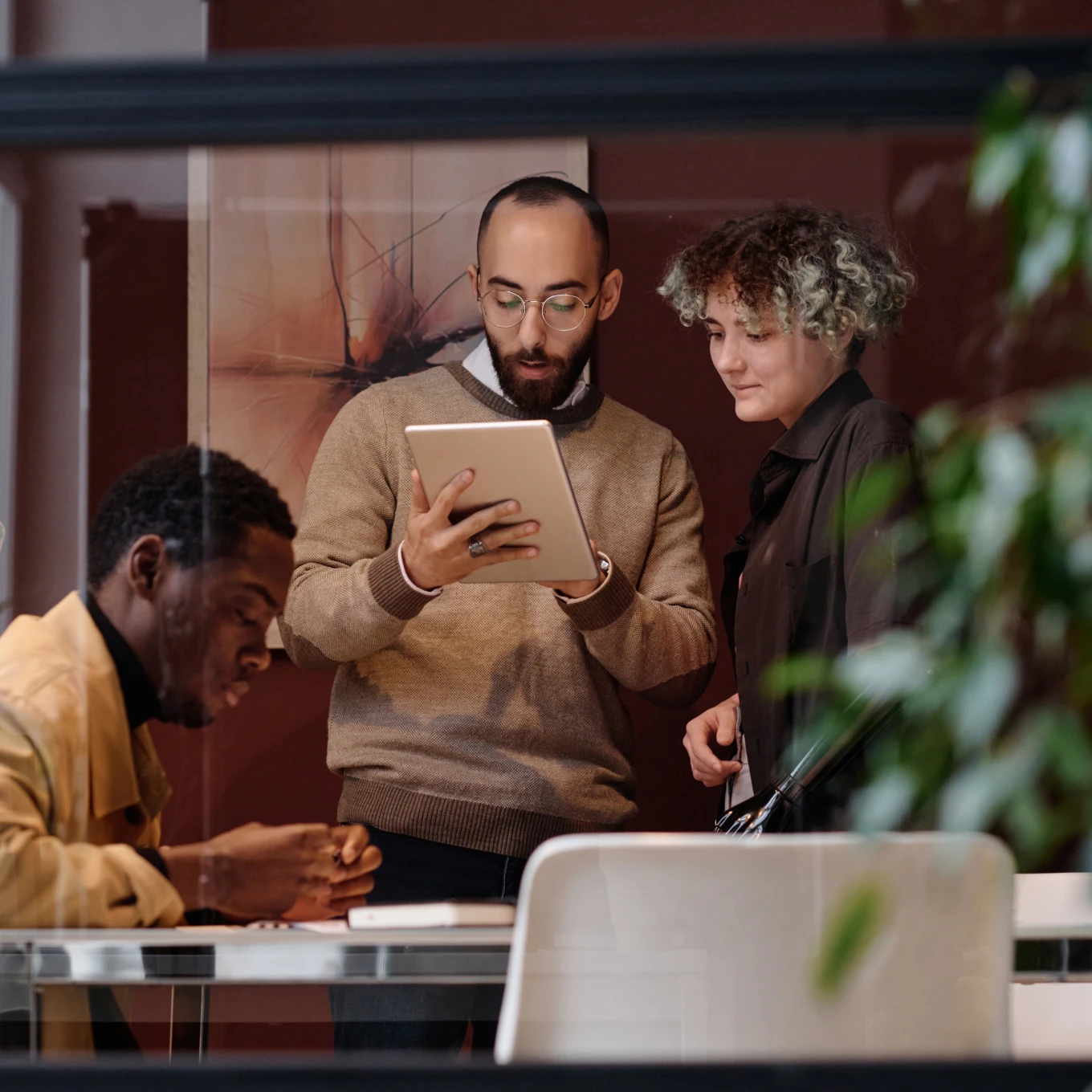 Three colleagues collaborating and reviewing content on a tablet