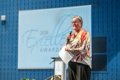Dr. Reid speaking at a podium at the 2024 Excellence Awards.