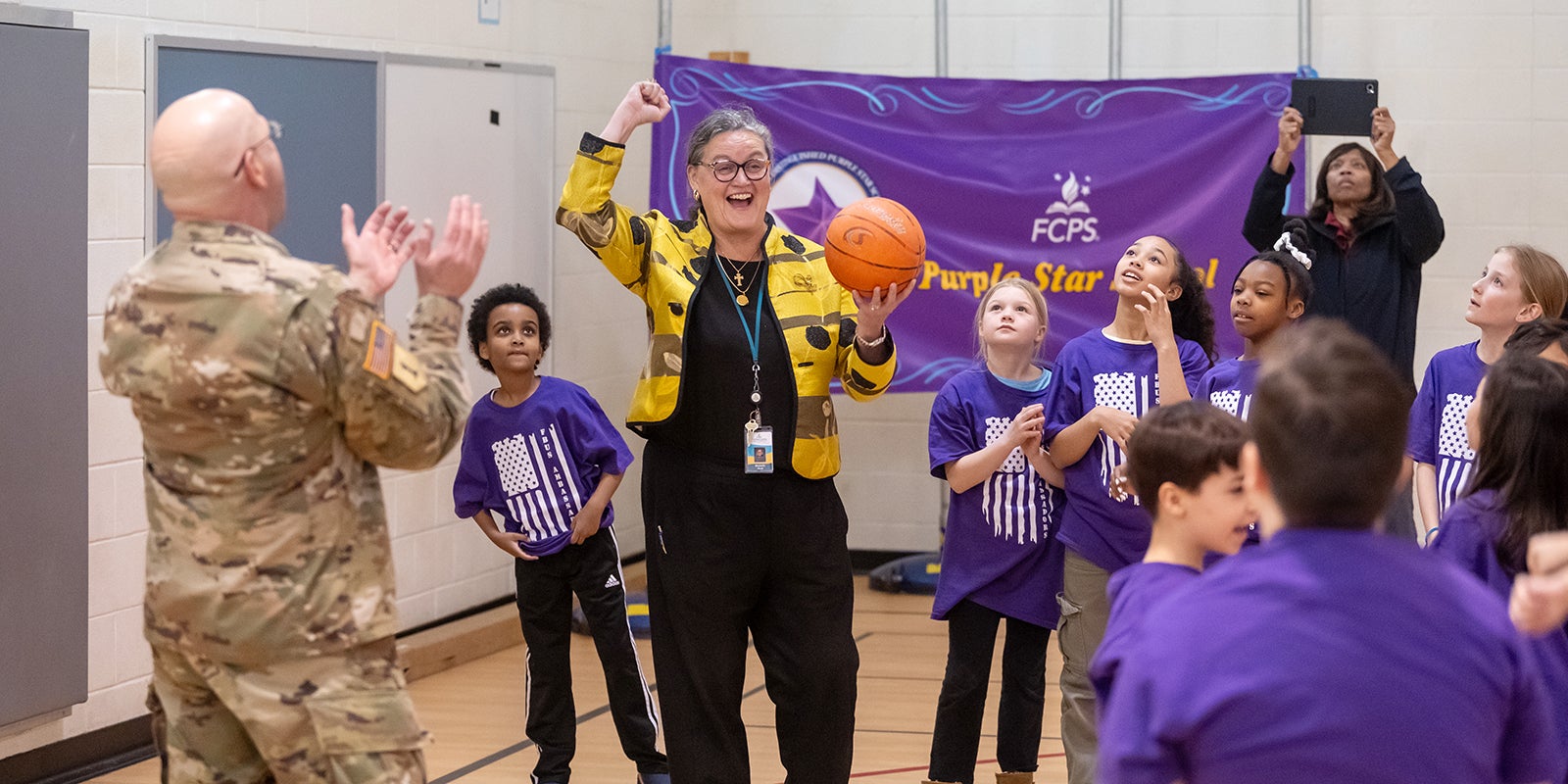 Dr. Reid plays basketball with students wearing purple and a military officer