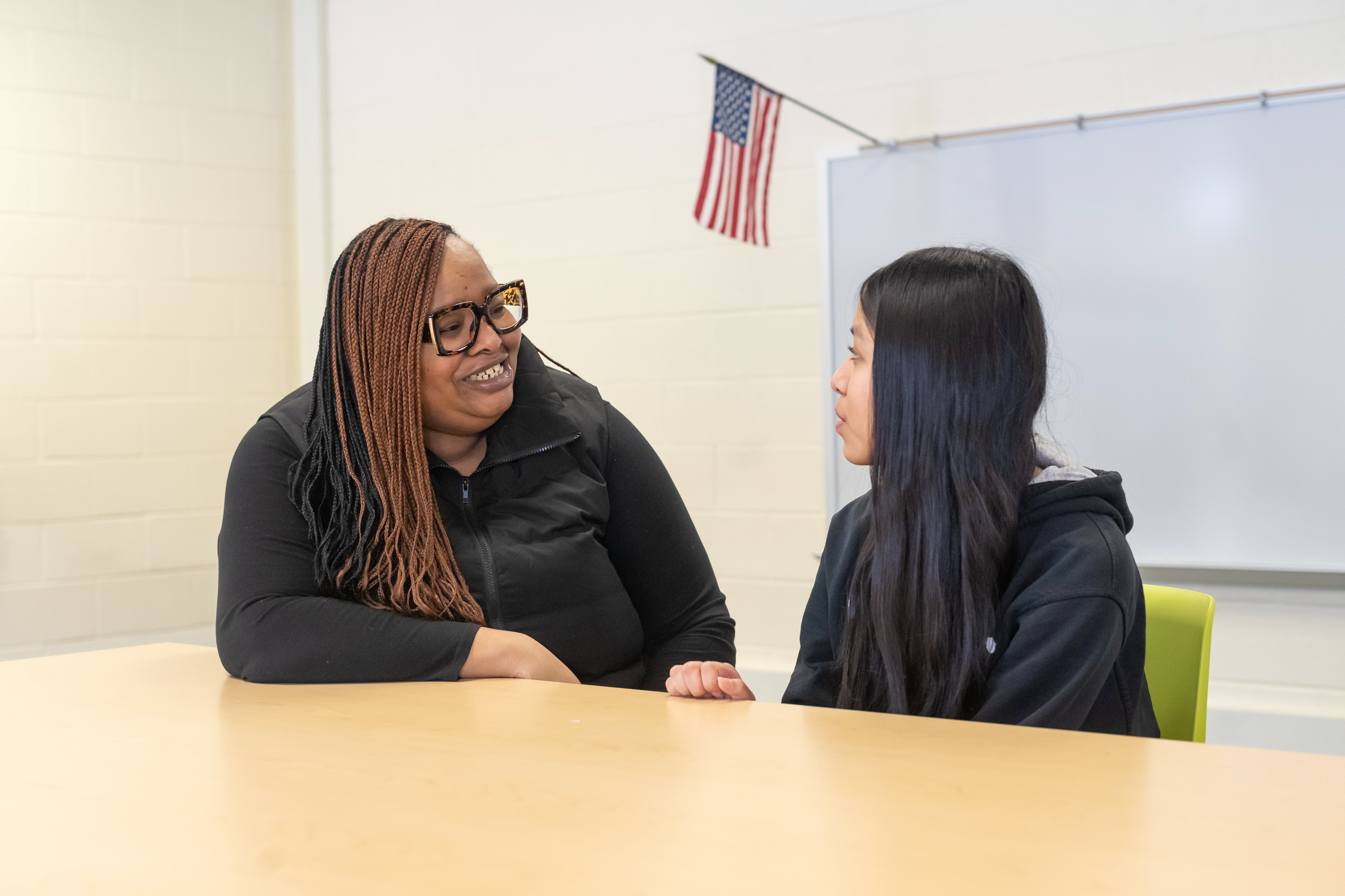 A woman, left, smiles as she speaks to a girl, right.