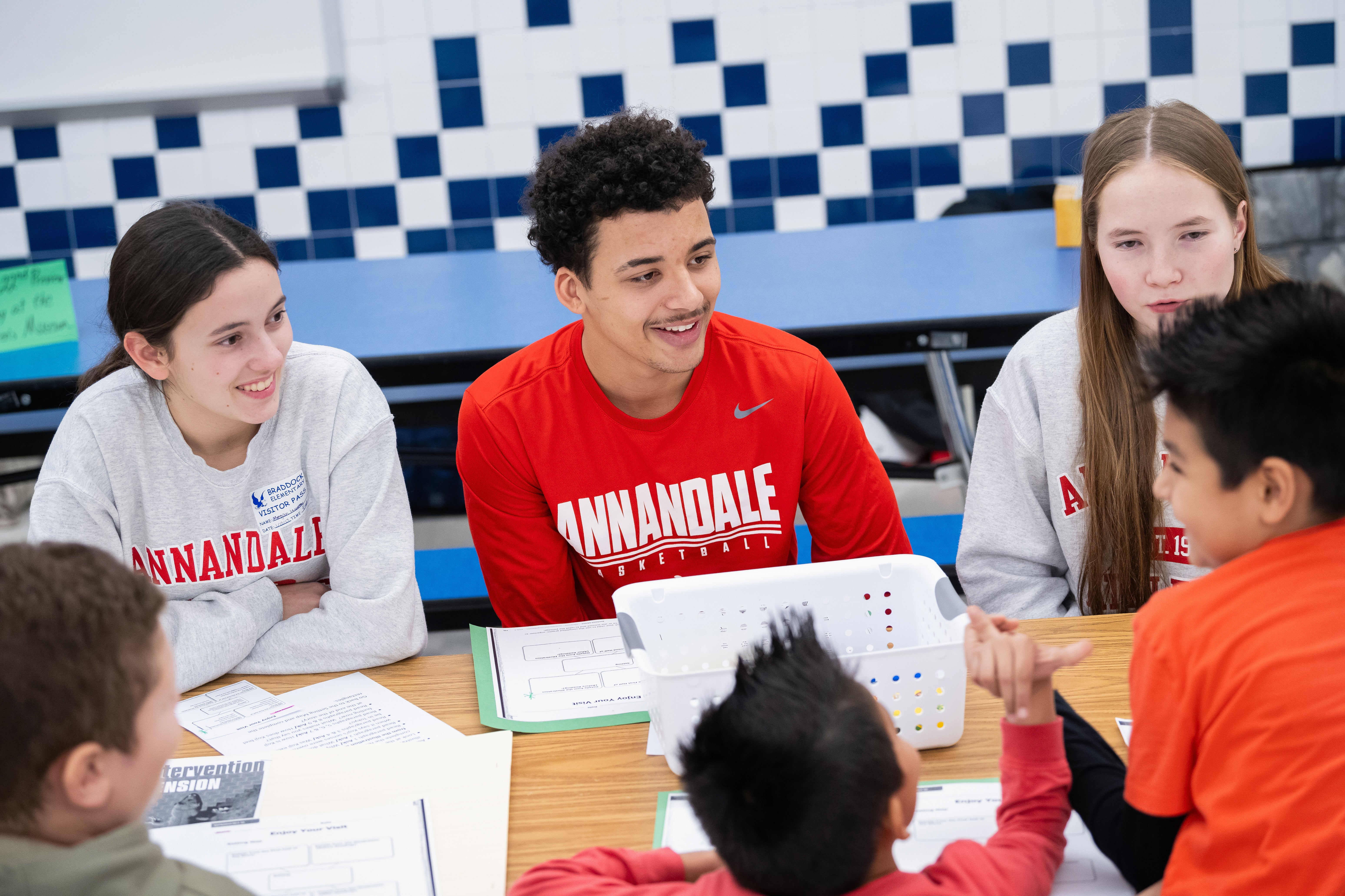 Annandale High School and Braddock Elementary School students smile as they work together on a reding lesson.