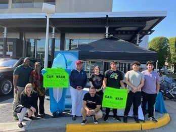 Dr. Reid with a group of students holding up car wash signs.
