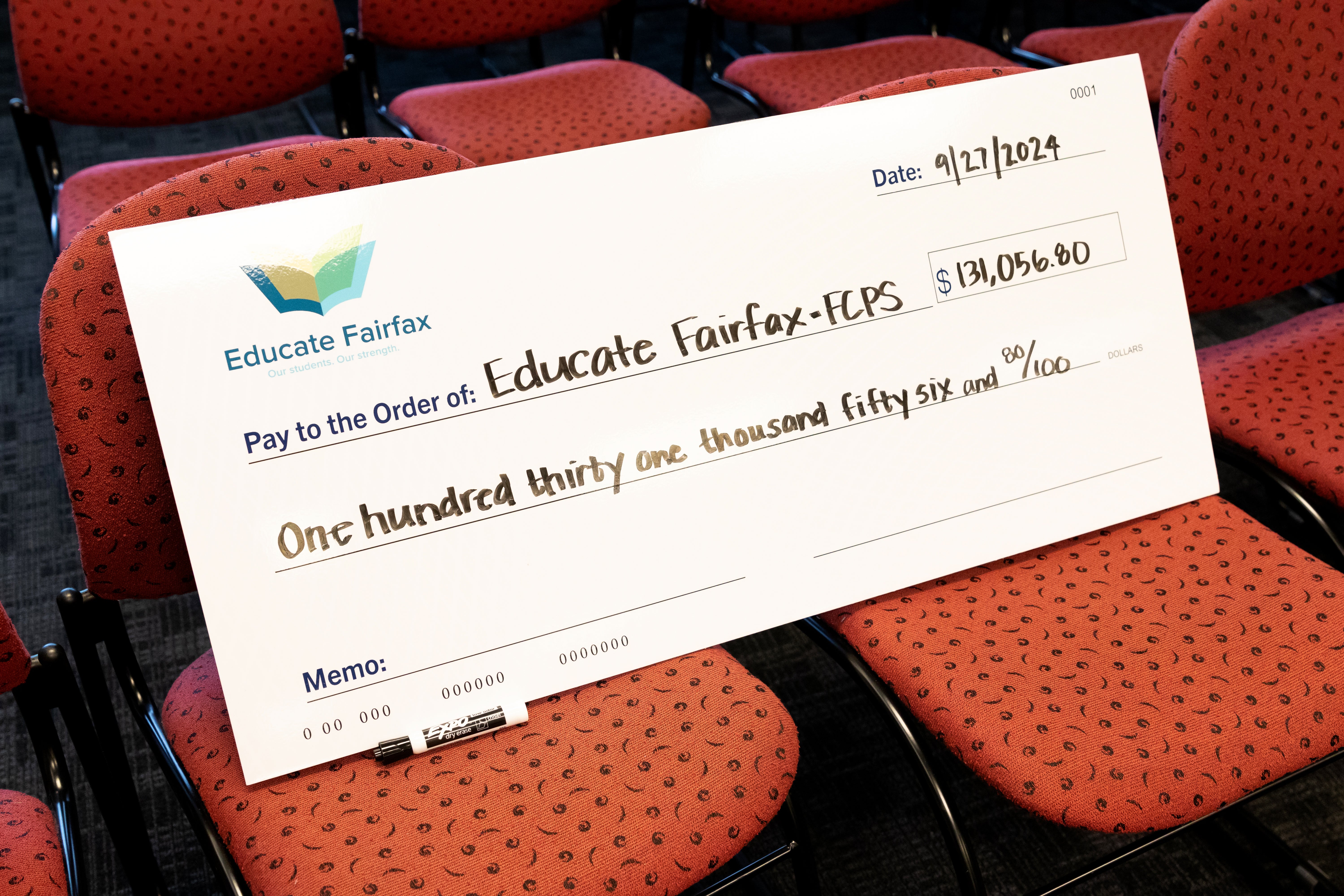 A giant novelty check lists the donation amount to Educate Fairfax: $131,056.80.