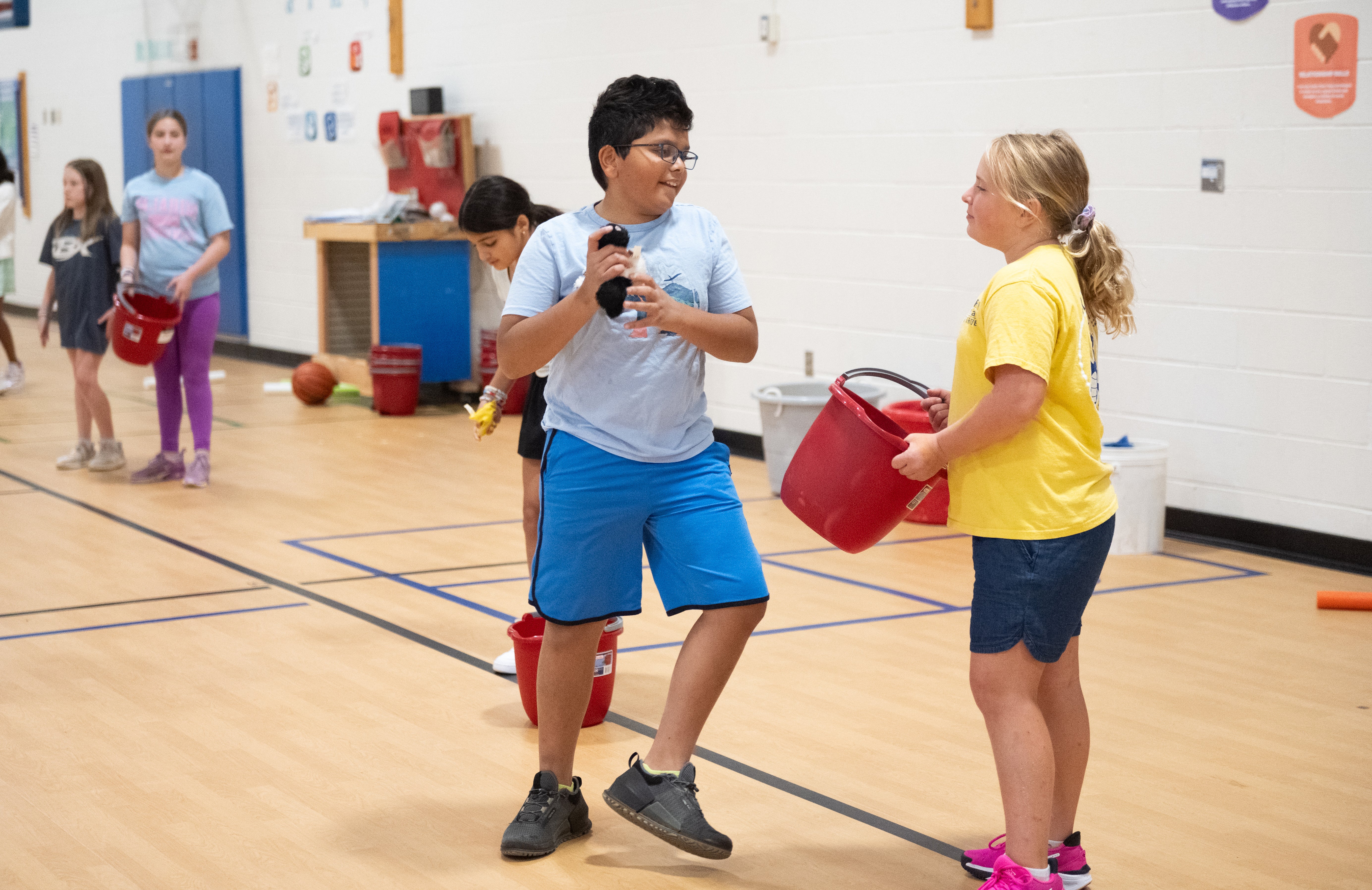 Two students chat as they work on a basketball skill together.