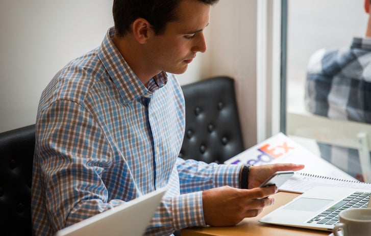 person looking at laptop with a coffee cup beside it